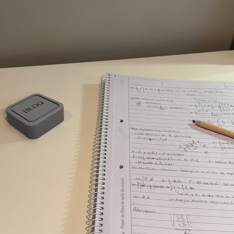 BLOQ sobre un escritorio junto a una libreta, listo para un bloque de foco